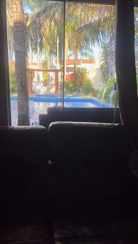 Vista da sala para a piscina, redes e pergolado